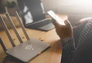 Person using laptop in coffee shop with public Wi-Fi security concerns
